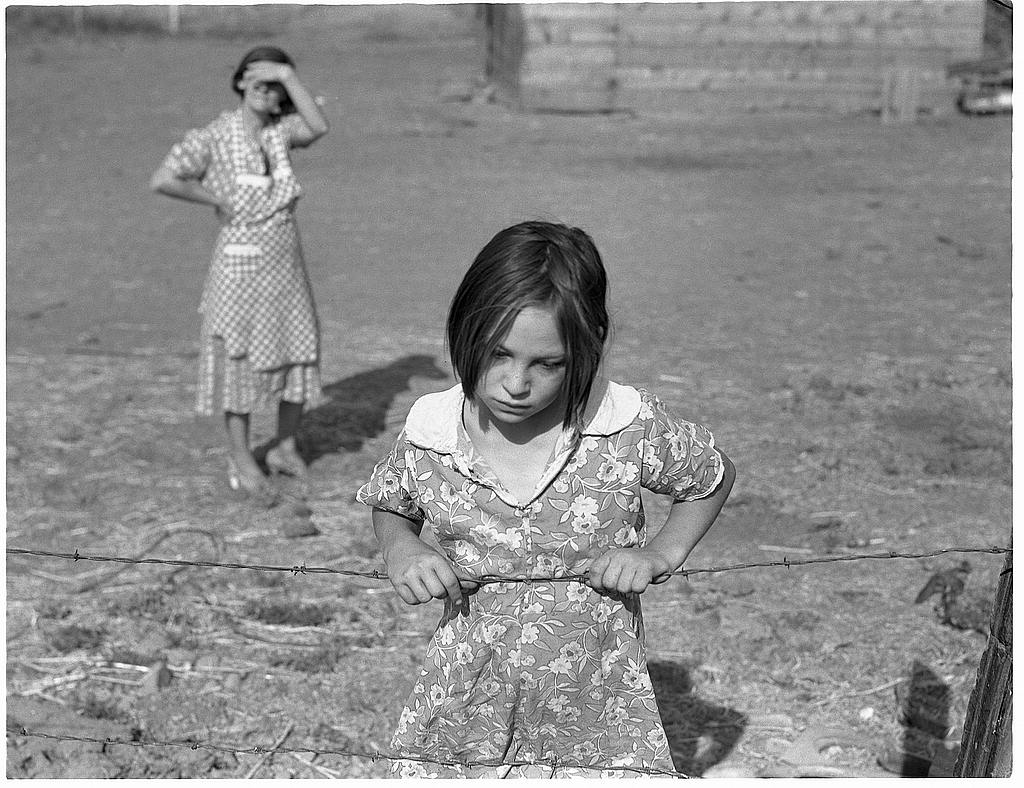 Niña detrás una alambrada, fotografiada por Dorothea Lange