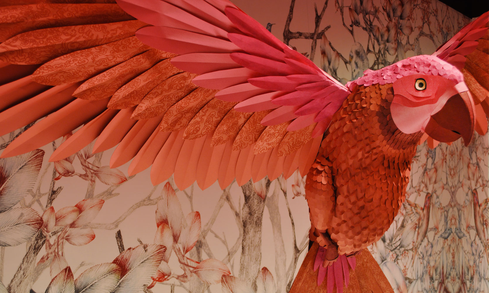 Detalle de una escultura de papel de un loro rojo