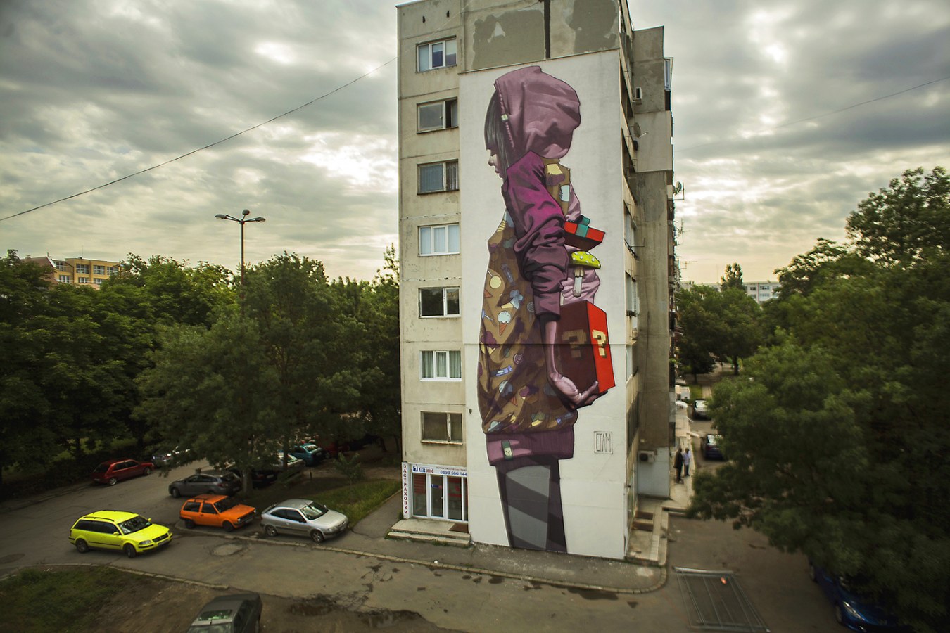 Mural en un edificio de etam cru donde sale una niña arabe con un regalo