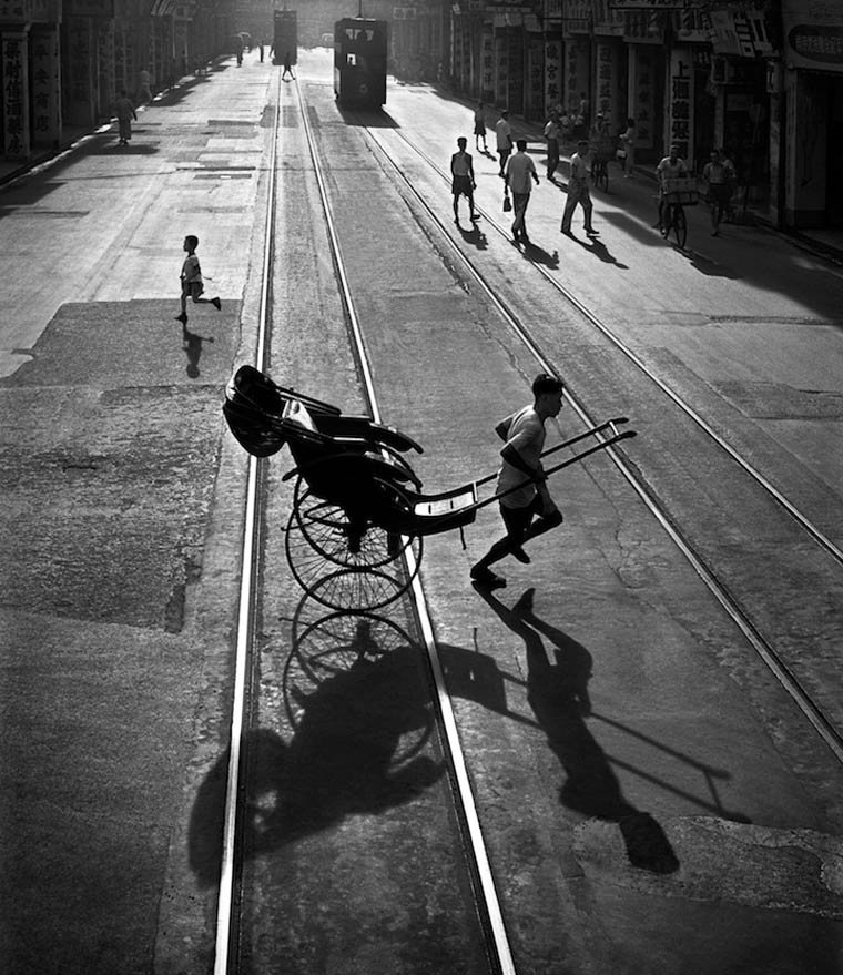 Fotografía en blanco y negro de chico con carrito en una calle de hong kong en el año 1960