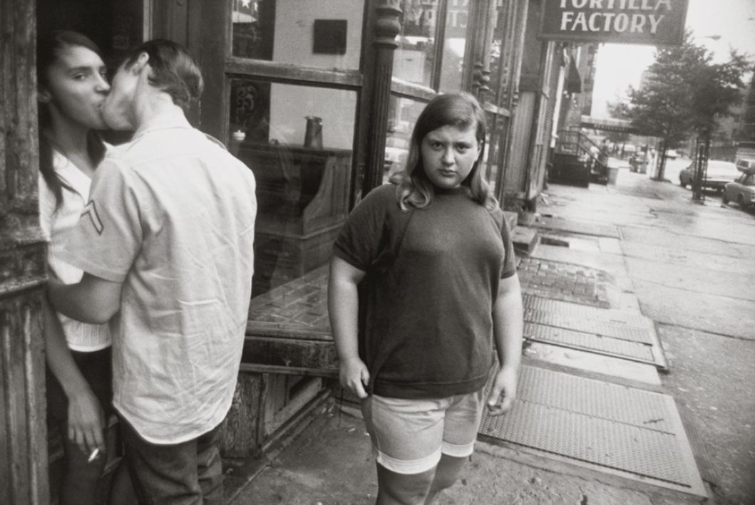 fotografía de Garry Winogrand de pareja de jovenes besandose y chico mirando a camara