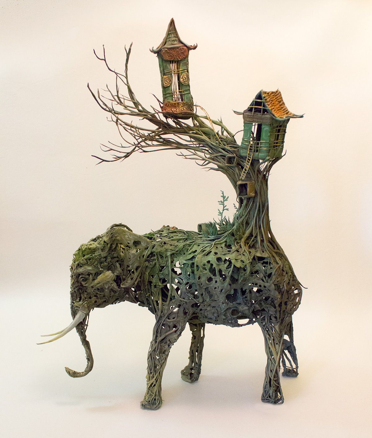 escultura de un elefante con la cola que son unas casa creada con plantas