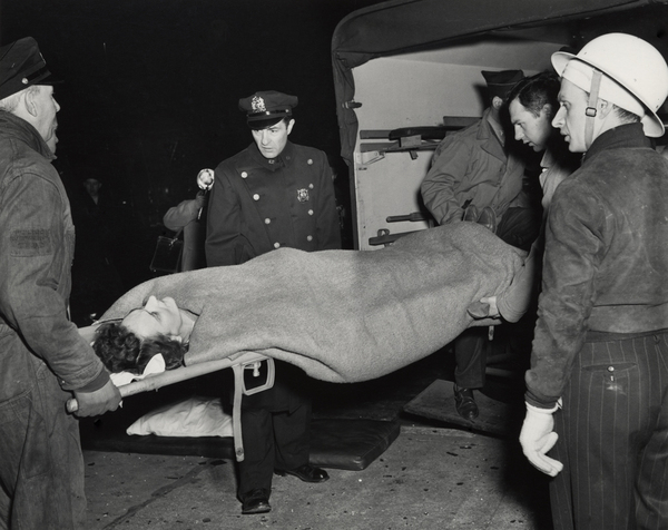 Weegee fotografía a un herido entrando a un ambulancia en 1944.