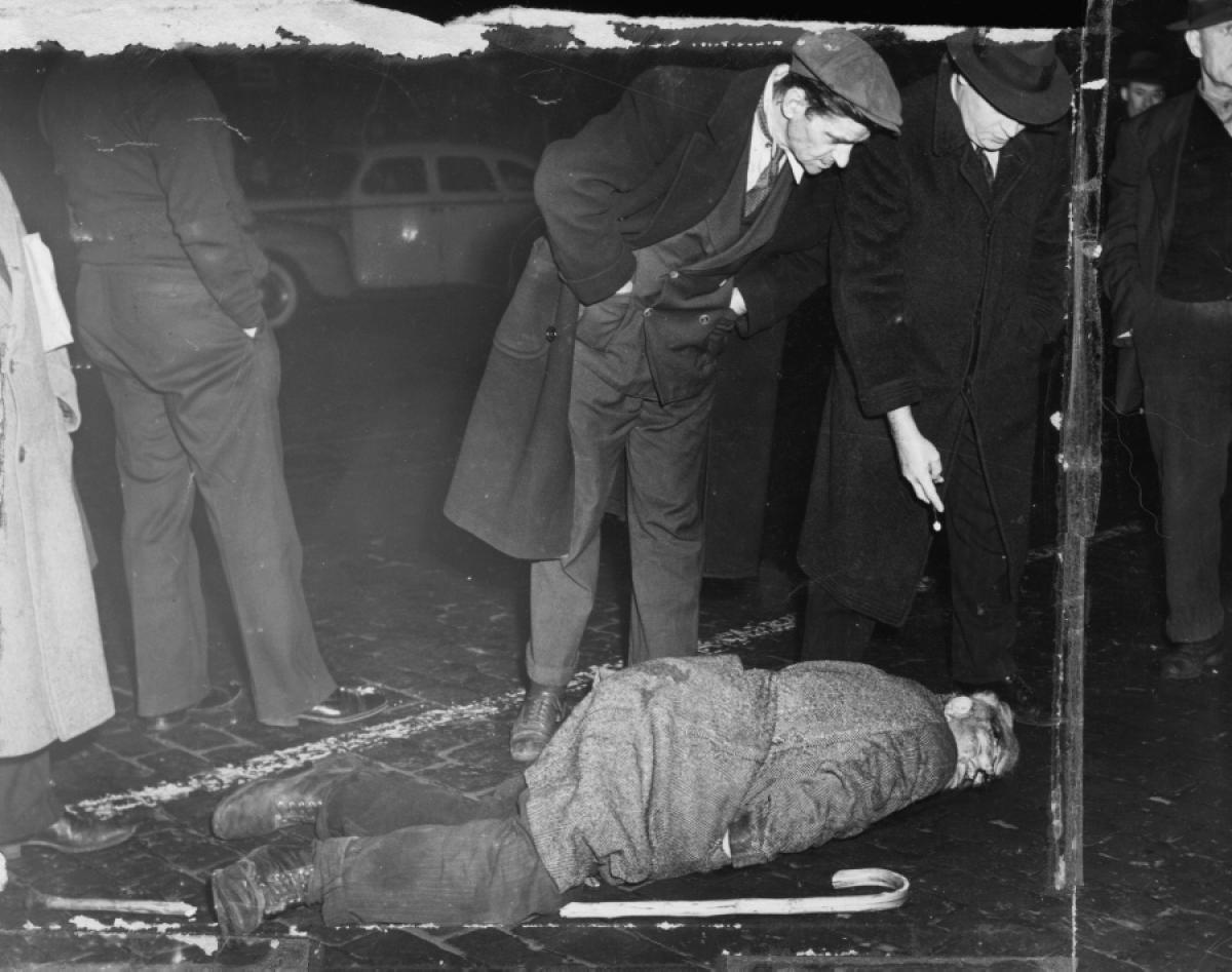 Policía levantando un cadaver en las calles del new york de 1940