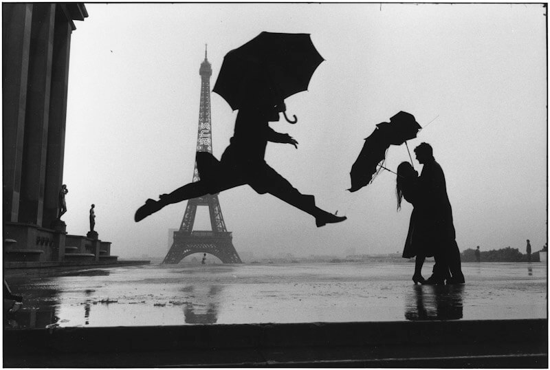 Foto de hombres con paraguas saltando delante de la torre eiffel en parís