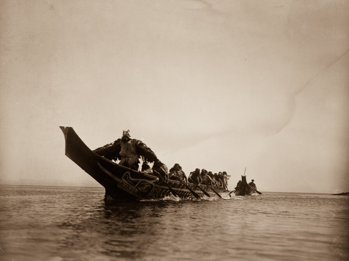 Indios nativo americanos en canoa atravesando un río