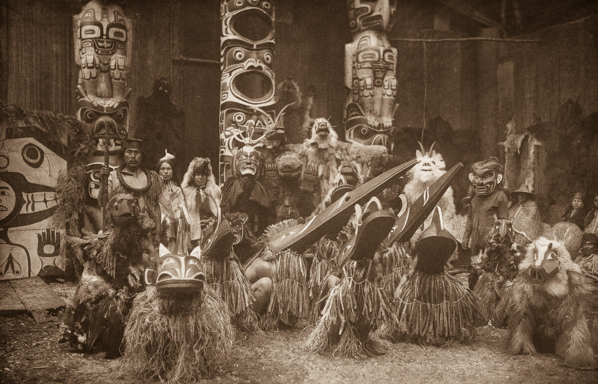 Indios nativos americanos disfrazados junto a un totem