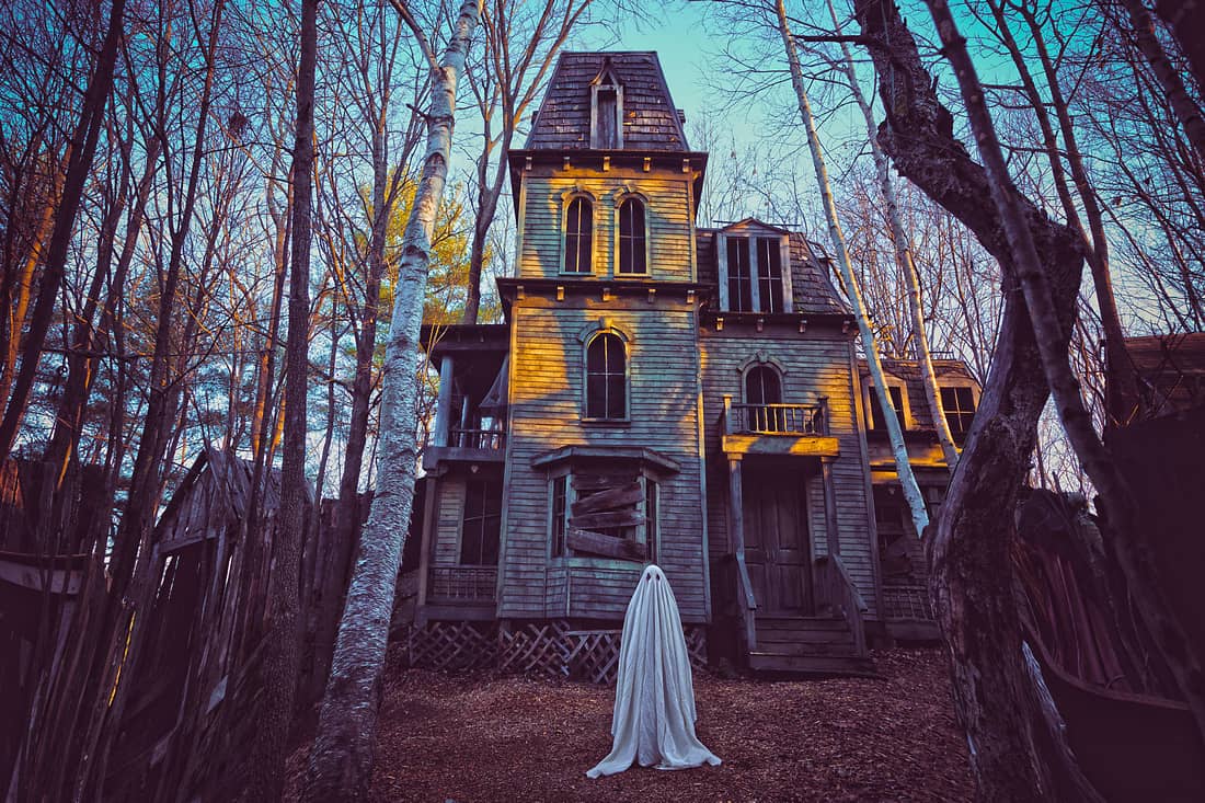 fotografía de un fantasma delante una casa abandonada